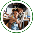 A mother hugs her young daughter from behind.  